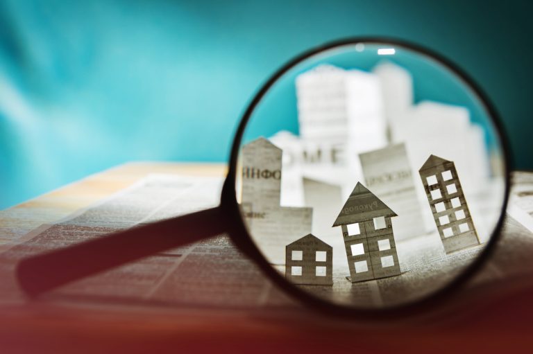 Apartment shopping, Apartment Mystery Shops, Apartment renters Journey A magnifying glass focuses on paper cutouts of buildings against a newspaper backdrop, suggesting the scrutiny involved in streamlining operations with property management software. Multifamily Journey Lens CX for the Apartment Industry